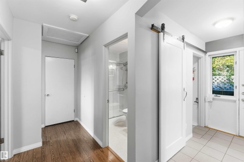 Hallway featuring a barn door leading to a separate area, wood-finish flooring, light gray walls, and a recessed ceiling access panel - 5208 105 Street Nw, Edmonton, AB - Indoor Photo Showing Other Room