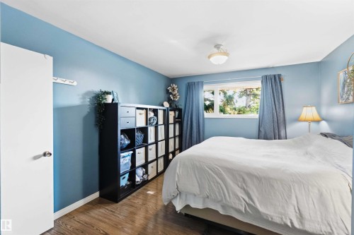 Bedroom featuring wood-finish flooring, a window with exterior tree views, and light blue wall tones - 5208 105 Street Nw, Edmonton, AB - Indoor Photo Showing Bedroom
