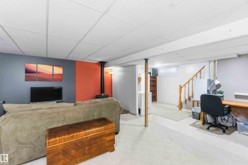 Spacious lower level featuring a drop ceiling, a freestanding wood stove, and a designated desk area - 5208 105 Street Nw, Edmonton, AB - Indoor