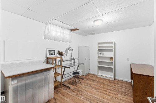 Spacious room featuring wood-finish flooring, white walls, and a drop ceiling with recessed lighting - 5208 105 Street Nw, Edmonton, AB - Indoor Photo Showing Other Room