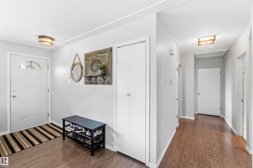 Entryway featuring wood-finish flooring, a white paneled entry door with decorative glass, two flush-mount ceiling lights, and painted walls - 5208 105 Street Nw, Edmonton, AB - Indoor Photo Showing Other Room