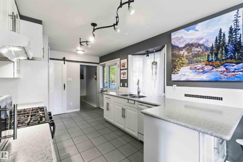 Contemporary kitchen featuring white cabinetry, gray square tile flooring, and light-toned countertops - 5208 105 Street Nw, Edmonton, AB - Indoor Photo Showing Kitchen With Double Sink