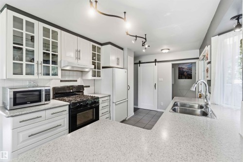 Kitchen featuring white cabinetry, light-colored countertops, and a double basin stainless steel sink with a gooseneck faucet - 5208 105 Street Nw, Edmonton, AB - Indoor Photo Showing Kitchen With Double Sink