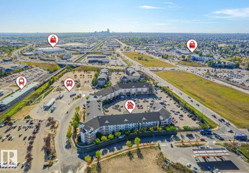 Aerial perspective showcasing residential buildings with ample surface parking, proximity to major roadways, and nearby commercial structures - #1418 330 Clareview Station Dr Nw, Edmonton, AB - Outdoor With View