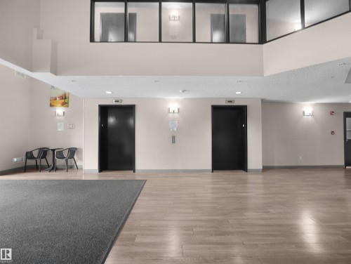 Lobby featuring wood-finish flooring, two elevators, and a two-story ceiling with interior windows - #1418 330 Clareview Station Dr Nw, Edmonton, AB - Indoor Photo Showing Other Room
