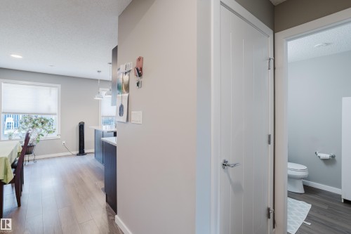 Hallway featuring a contemporary white door with chrome hardware, wood-finish flooring, and light gray wall paint - #28 2215 24 St Nw, Edmonton, AB - Indoor