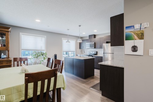 Open-concept living space featuring wood-finish flooring, recessed lighting, and a modern kitchen - #28 2215 24 St Nw, Edmonton, AB - Indoor