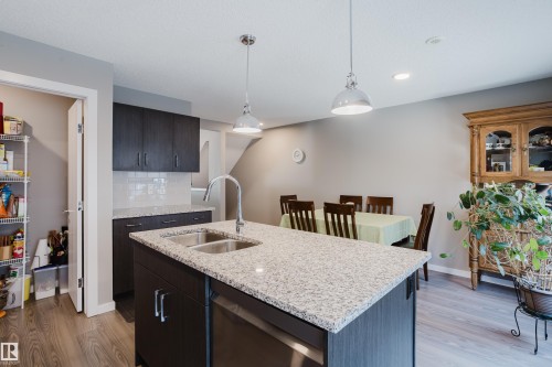 Kitchen island with a double basin stainless steel sink, a chrome faucet, and pendant lighting - #28 2215 24 St Nw, Edmonton, AB - Indoor Photo Showing Kitchen With Double Sink