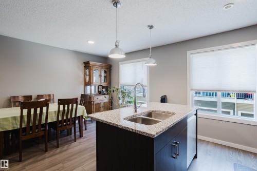 Kitchen island featuring a double basin stainless steel sink, gooseneck faucet, and granite-style countertop - #28 2215 24 St Nw, Edmonton, AB - Indoor