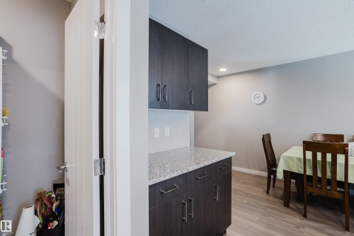 Kitchenette featuring dark wood-finish cabinetry, light speckled countertop, and light gray backsplash - #28 2215 24 St Nw, Edmonton, AB - Indoor