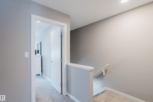 Carpeted hallway with light gray walls and white trim - #28 2215 24 St Nw, Edmonton, AB - Indoor Photo Showing Other Room