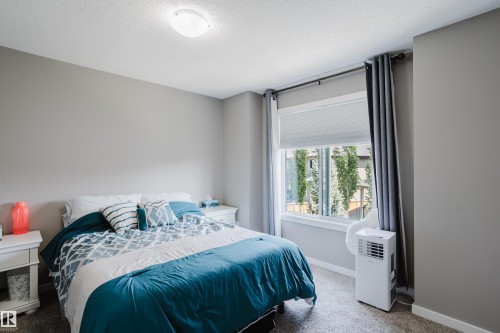 Bedroom featuring neutral wall paint, a frosted flush-mount ceiling light, a large window with roller shades, and dark grey curtain rods - #28 2215 24 St Nw, Edmonton, AB - Indoor Photo Showing Bedroom