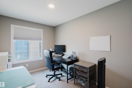 Carpeted room featuring a white-framed window with a roller shade, recessed ceiling lighting, and neutral wall paint - #28 2215 24 St Nw, Edmonton, AB - Indoor Photo Showing Office
