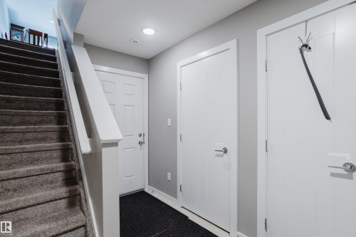 Carpeted staircase with white balustrade, recessed lighting, and multiple white panel doors - #28 2215 24 St Nw, Edmonton, AB - Indoor Photo Showing Other Room