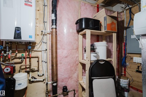 Tankless water heater installation with visible plumbing and insulation - #28 2215 24 St Nw, Edmonton, AB - Indoor Photo Showing Basement