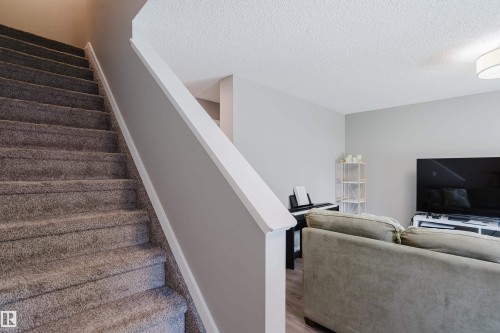 Carpeted staircase with white trim, light gray wall paint, and textured ceiling - #28 2215 24 St Nw, Edmonton, AB - Indoor Photo Showing Other Room