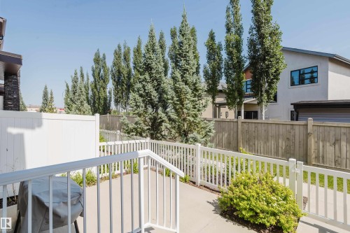 Outdoor patio area featuring a white picket fence, concrete paving, and a small shrub - #28 2215 24 St Nw, Edmonton, AB - Outdoor With Exterior