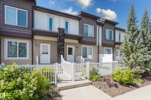 Contemporary townhome exterior featuring multi-toned siding, white trim, and a prominent stone accent column - #28 2215 24 St Nw, Edmonton, AB - Outdoor With Facade