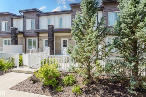 Modern townhome exterior featuring multi-toned siding, white trim, and stone column accents - #28 2215 24 St Nw, Edmonton, AB - Outdoor With Facade