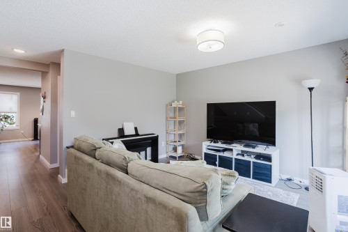 Living area featuring wood-finish flooring, light grey painted walls, and a contemporary flush-mount ceiling light - #28 2215 24 St Nw, Edmonton, AB - Indoor Photo Showing Living Room