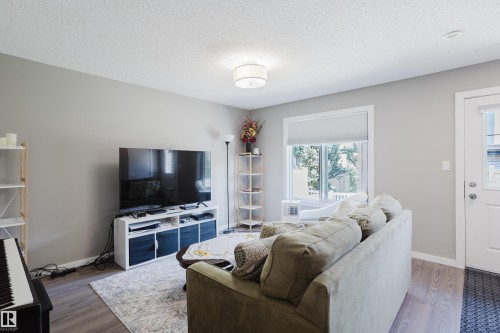 Bright living space featuring wood-finish flooring, light grey walls, and a white ceiling - #28 2215 24 St Nw, Edmonton, AB - Indoor