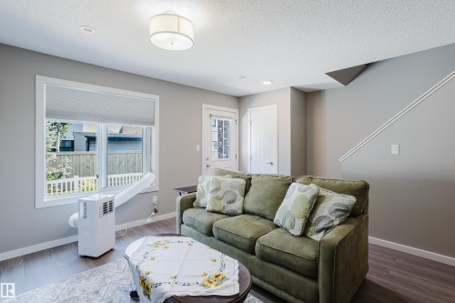 Spacious living area featuring wood-finish flooring, recessed lighting, and a drum pendant light fixture - #28 2215 24 St Nw, Edmonton, AB - Indoor Photo Showing Living Room