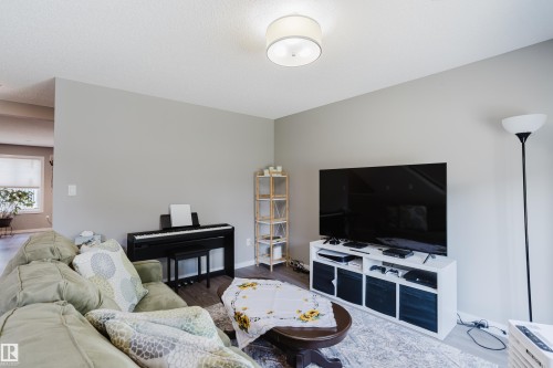 Living area with light gray walls, wood-finish flooring, and a contemporary flush-mount ceiling light - #28 2215 24 St Nw, Edmonton, AB - Indoor Photo Showing Living Room