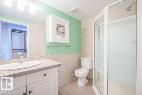White vanity with an integrated sink, brushed nickel faucet, and a framed mirror - #108 12028 103 Av Nw, Edmonton, AB 