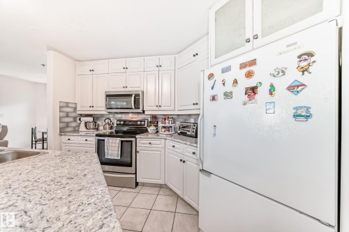White cabinetry with dark hardware and a tile backsplash - #108 12028 103 Av Nw, Edmonton, AB 