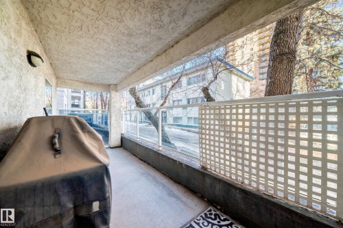 Private balcony with textured ceiling, concrete flooring, and glass panel railing - #108 12028 103 Av Nw, Edmonton, AB 