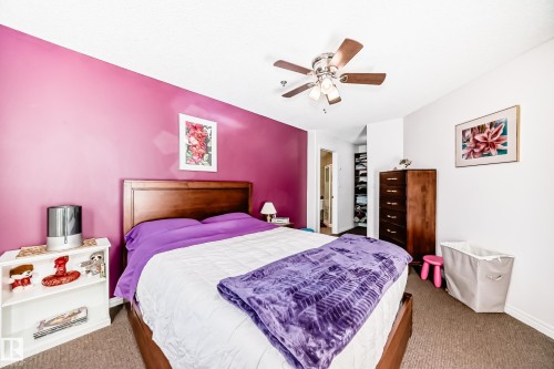 Wood-finish bed frame, carpeted flooring, and a ceiling fan with integrated lighting - #108 12028 103 Av Nw, Edmonton, AB 