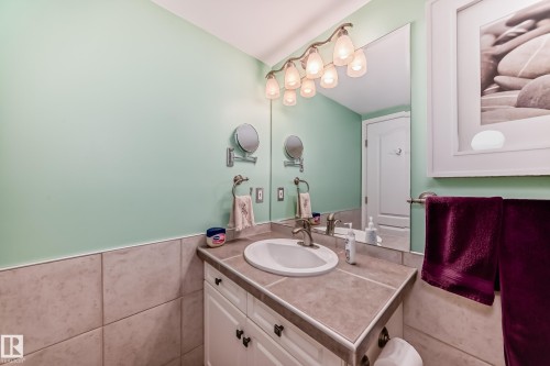 Vanity with integrated sink, tiled countertop, and wall-mounted mirror - #108 12028 103 Av Nw, Edmonton, AB 