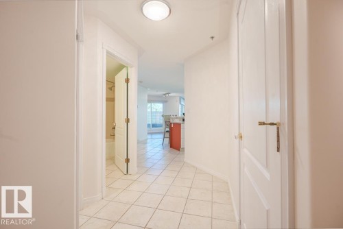 Recessed lighting illuminating the hallway with white tile flooring and white paneled doors - #108 12028 103 Av Nw, Edmonton, AB 
