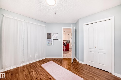 Wood-finish flooring throughout, complemented by a bi-fold closet door - #108 12028 103 Av Nw, Edmonton, AB 