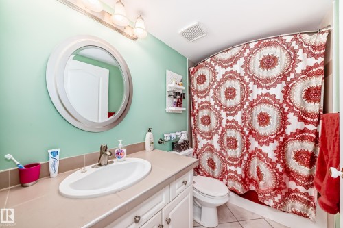 Vanity with an integrated oval sink, chrome-finish faucet, and a round mirror - #108 12028 103 Av Nw, Edmonton, AB 