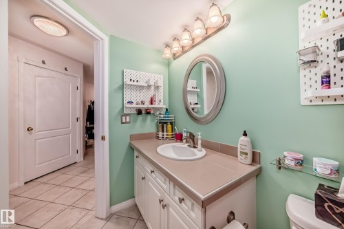 Vanity with integrated sink, ample storage cabinetry, and an oval mirror - #108 12028 103 Av Nw, Edmonton, AB 