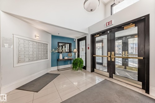 Entryway with large format tile flooring, a built-in mail station, a feature wall, and full-light double entry doors - #108 12028 103 Av Nw, Edmonton, AB 