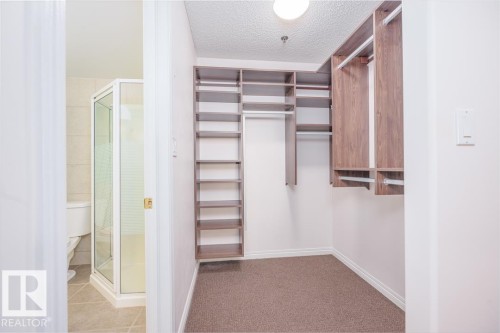Walk-in closet with built-in wood-finish shelving and hanging rods - #108 12028 103 Av Nw, Edmonton, AB 