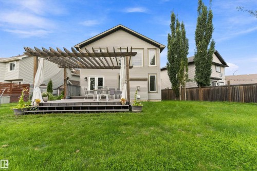 Expansive green lawn with a multi-level composite deck, featuring a wooden pergola with fabric accents - 20845 92A Avenue Nw, Edmonton, AB - Outdoor With Deck Patio Veranda