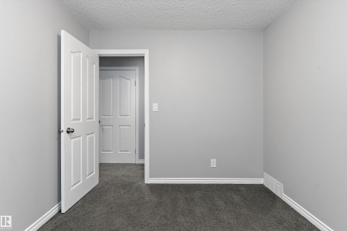 Neutral gray wall paint with white trim, dark gray carpeting, and white paneled doors - 20845 92A Avenue Nw, Edmonton, AB - Indoor Photo Showing Other Room