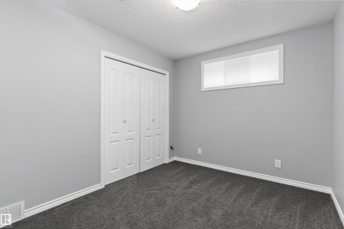 Recessed window with white blinds, neutral wall paint, white bi-fold closet doors, and plush dark gray carpeting - 20845 92A Avenue Nw, Edmonton, AB - Indoor Photo Showing Other Room