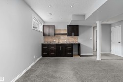 Recessed lighting, light gray wall paint, dark wood-finish cabinetry, built-in sink, and light gray carpeting - 
