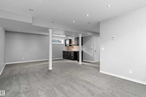 Expansive carpeted area featuring recessed lighting, a built-in wet bar with dark cabinetry, a neutral-toned backsplash, and an egress window - 20845 92A Avenue Nw, Edmonton, AB - Indoor