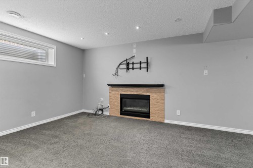 Recessed lighting, light gray walls, fireplace with tile surround, window well, and gray carpeting - 20845 92A Avenue Nw, Edmonton, AB - Indoor With Fireplace