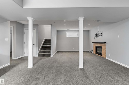 Spacious lower-level area featuring recessed lighting, a built-in fireplace with a stone surround, and carpeted flooring - 20845 92A Avenue Nw, Edmonton, AB - Indoor With Fireplace