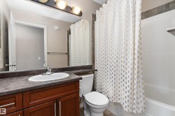 Built-in vanity with wood-finish cabinetry, a single basin sink, and a dark countertop - 