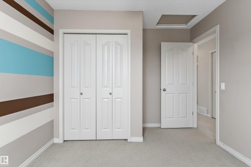 Neutral carpeting, white bi-fold closet doors, and painted walls with a striped accent - 20845 92A Avenue Nw, Edmonton, AB - Indoor