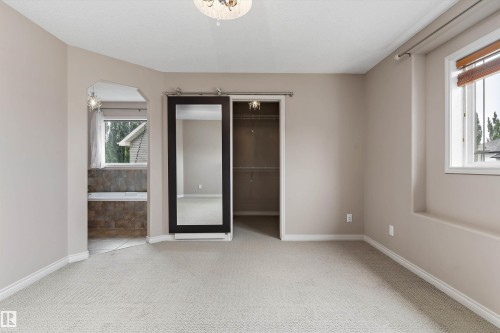 Plush carpeting, arched doorway, sliding barn door with full-length mirror, recessed window, and ceiling-mounted light fixture - 20845 92A Avenue Nw, Edmonton, AB - Indoor Photo Showing Other Room