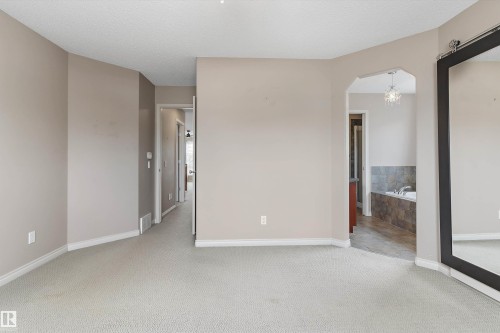 Plush carpet flooring, neutral wall tones, arched doorway, recessed lighting, and a built-in soaking tub with tile surround - 20845 92A Avenue Nw, Edmonton, AB - Indoor Photo Showing Other Room