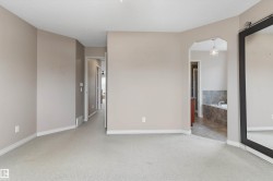 Plush carpet flooring, neutral wall tones, arched doorway, recessed lighting, and a built-in soaking tub with tile surround - 